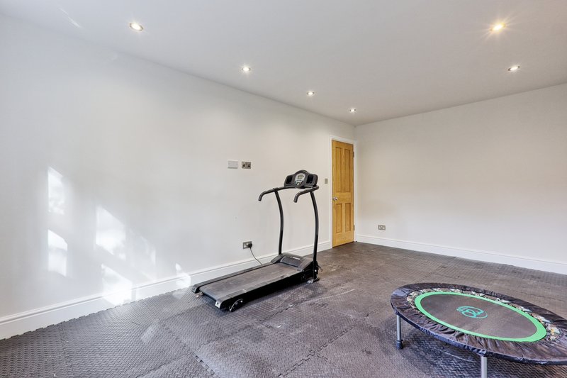 Home gym with treadmill, trampoline, recessed lighting and wooden door