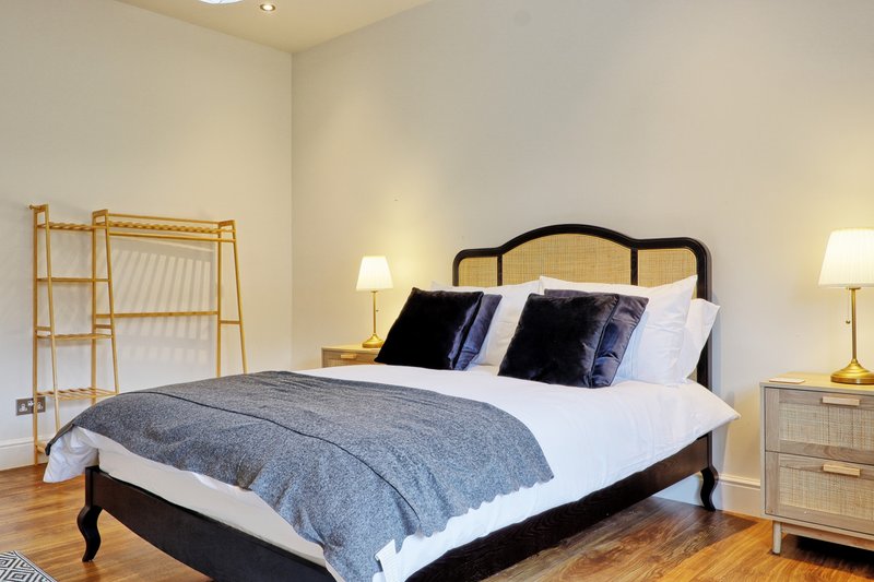 Bedroom with black metal bed frame, blue bedding, wooden nightstands, and decorative ladder