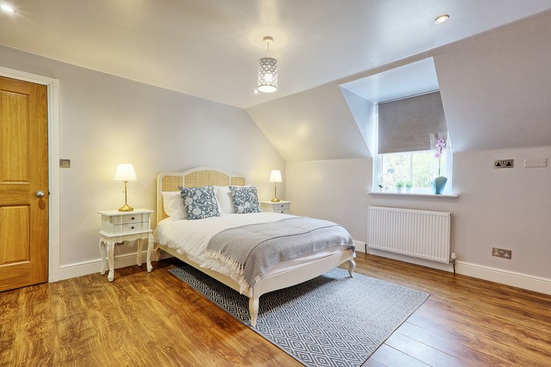 Bright attic bedroom with double bed, wooden floor, skylight window and cream furniture