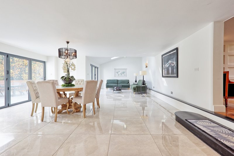 Open-plan living space with dining table, cream chairs, and modern furnishings throughout