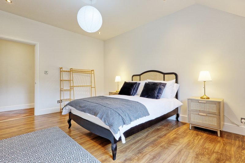 Bright bedroom with double bed, wooden floor, bedside tables and modern ceiling light