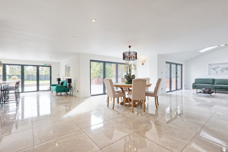 Bright open-plan living space with polished marble flooring, dining table, and contemporary furnishings