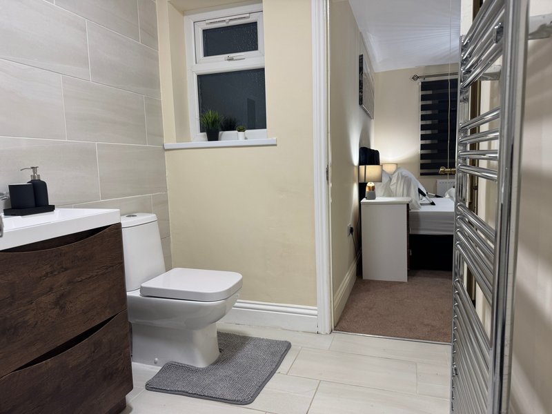 Modern bathroom with toilet, sink vanity, heated towel rail and window