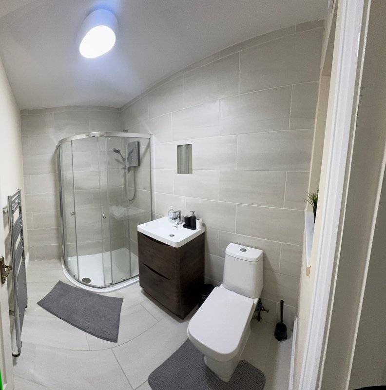 Modern bathroom with curved shower enclosure, vanity sink, toilet and heated towel rail
