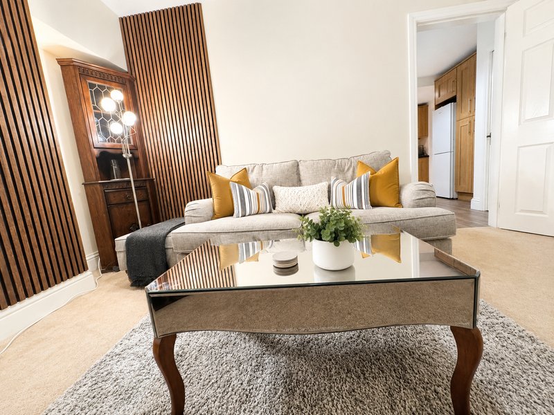 Modern living room with grey sofa, wooden coffee table, decorative cushions and plant