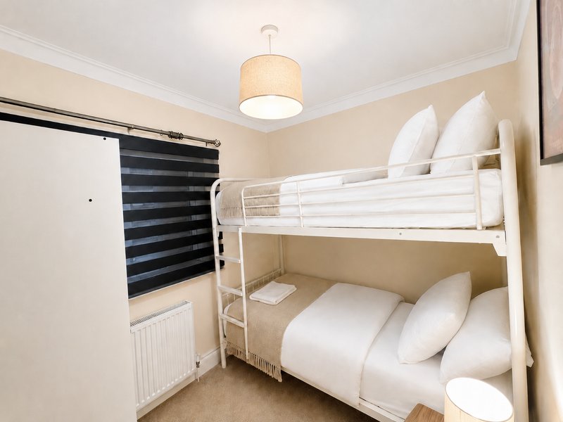 Bedroom with white metal bunk beds, striped window blinds, pendant light fixture