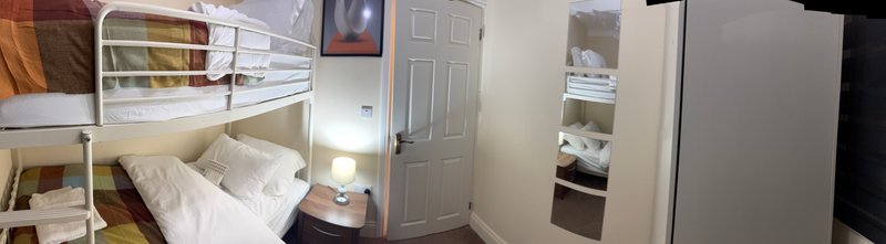 Compact bedroom with single bed, shelving unit, wardrobe and door