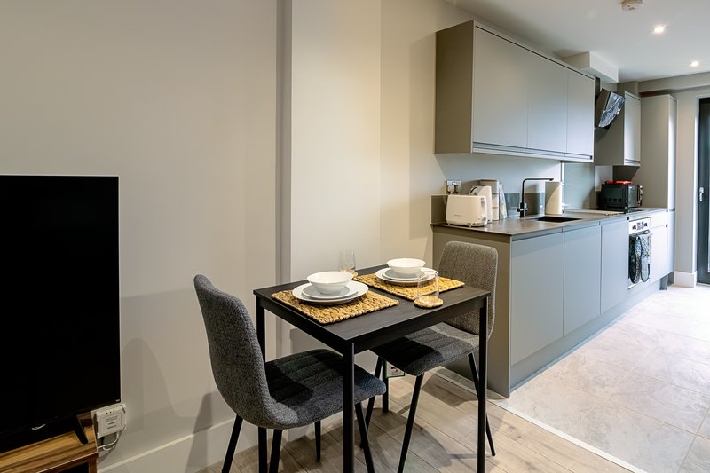 Modern kitchen-diner with black table, grey chairs, and fitted appliances