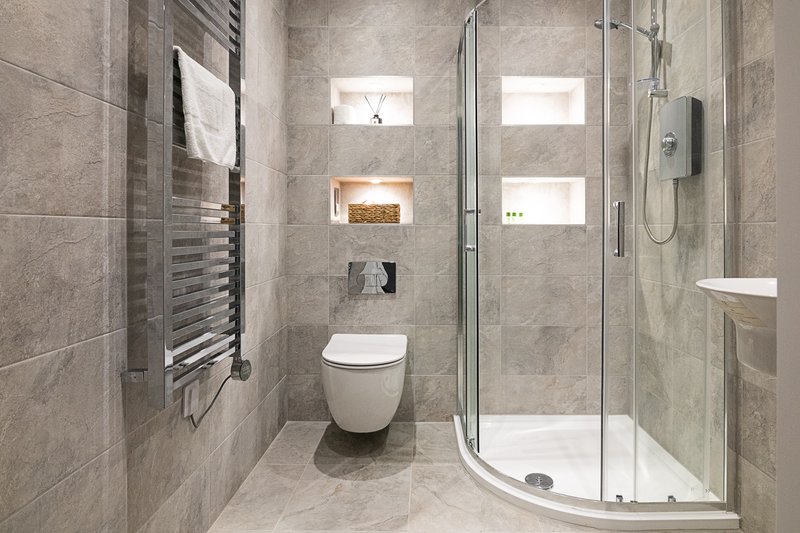 Modern bathroom with walk-in shower, wall-mounted toilet, heated towel rail and stone tiling