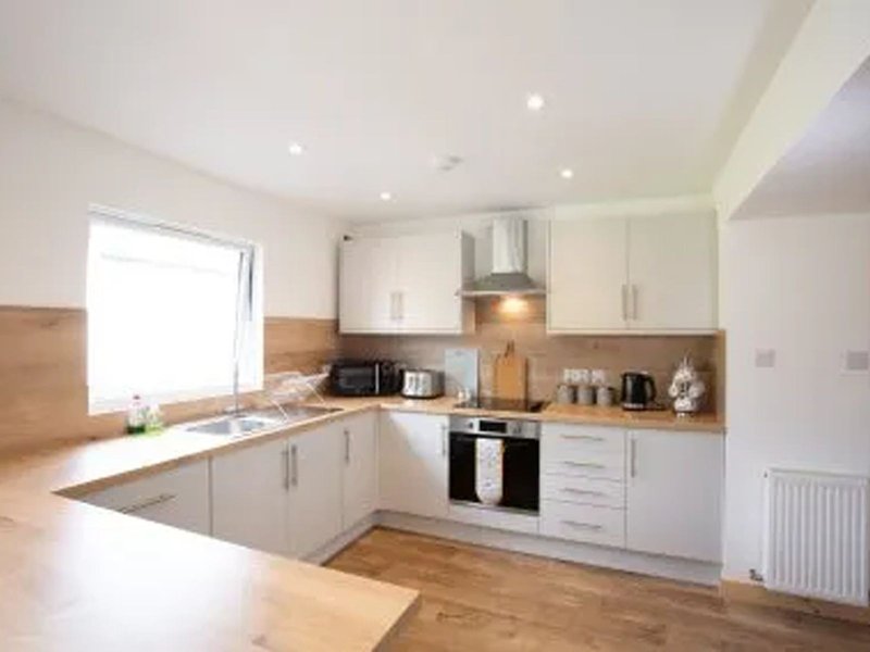 Modern kitchen with white cabinetry, wooden worktops, island, and stainless steel appliances