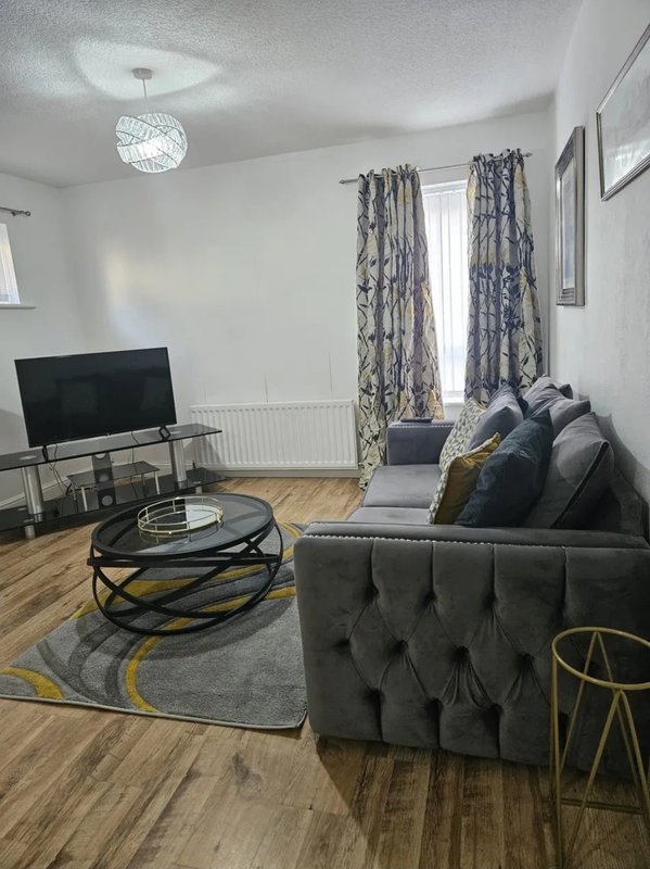 Modern living room with grey sofa, TV stand, round coffee table and patterned curtains