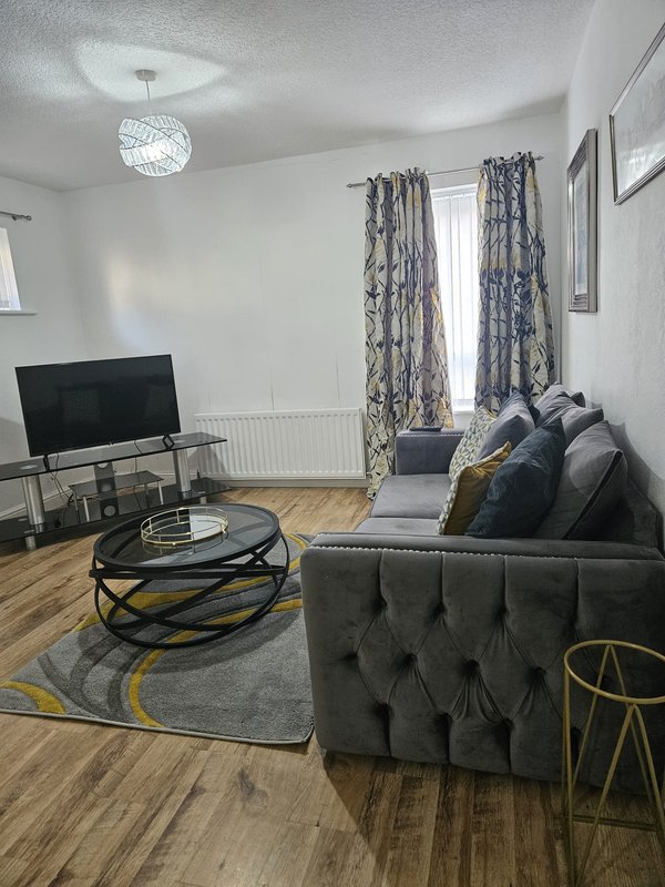 Modern living room with gray sofa, TV stand, coffee table, and patterned curtains