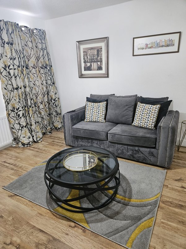 Living room with grey sofa, patterned curtains, round black coffee table and geometric rug