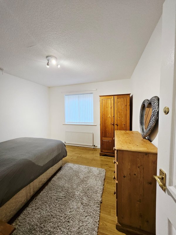 Bedroom with single bed, wooden dresser, wardrobe, window and wooden flooring