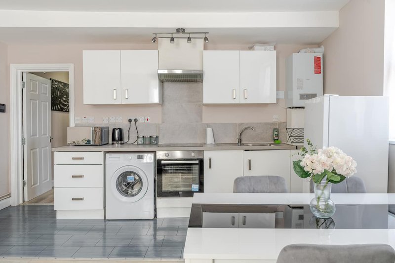 Modern kitchen with white cabinetry, integrated appliances, grey countertops and island with flowers