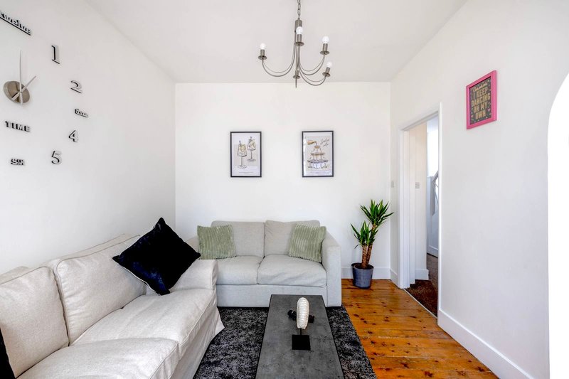 Bright living room with cream sofa, grey armchair, wooden flooring, and decorative wall art