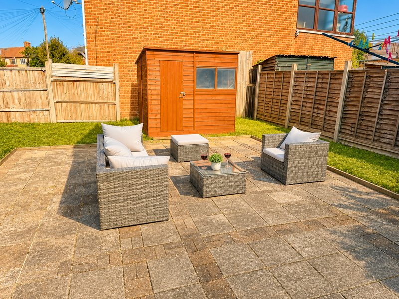 Brick house with patio garden furniture, shed, and wooden fencing