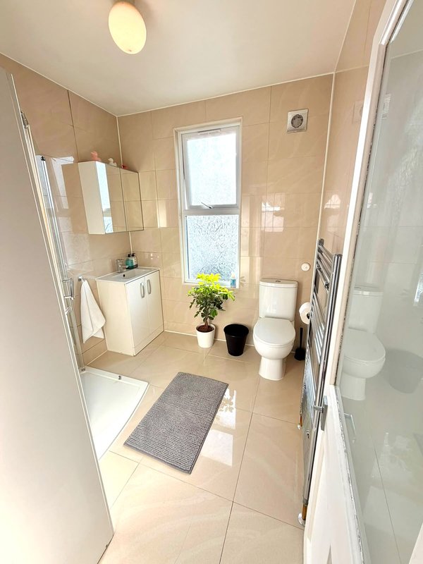 Modern bathroom with shower enclosure, vanity sink, toilet, window and heated towel rail