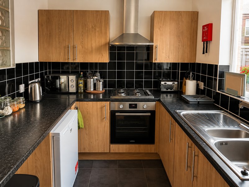 Modern kitchen with wooden cabinets, black tile backsplash, stainless steel appliances and dark countertops