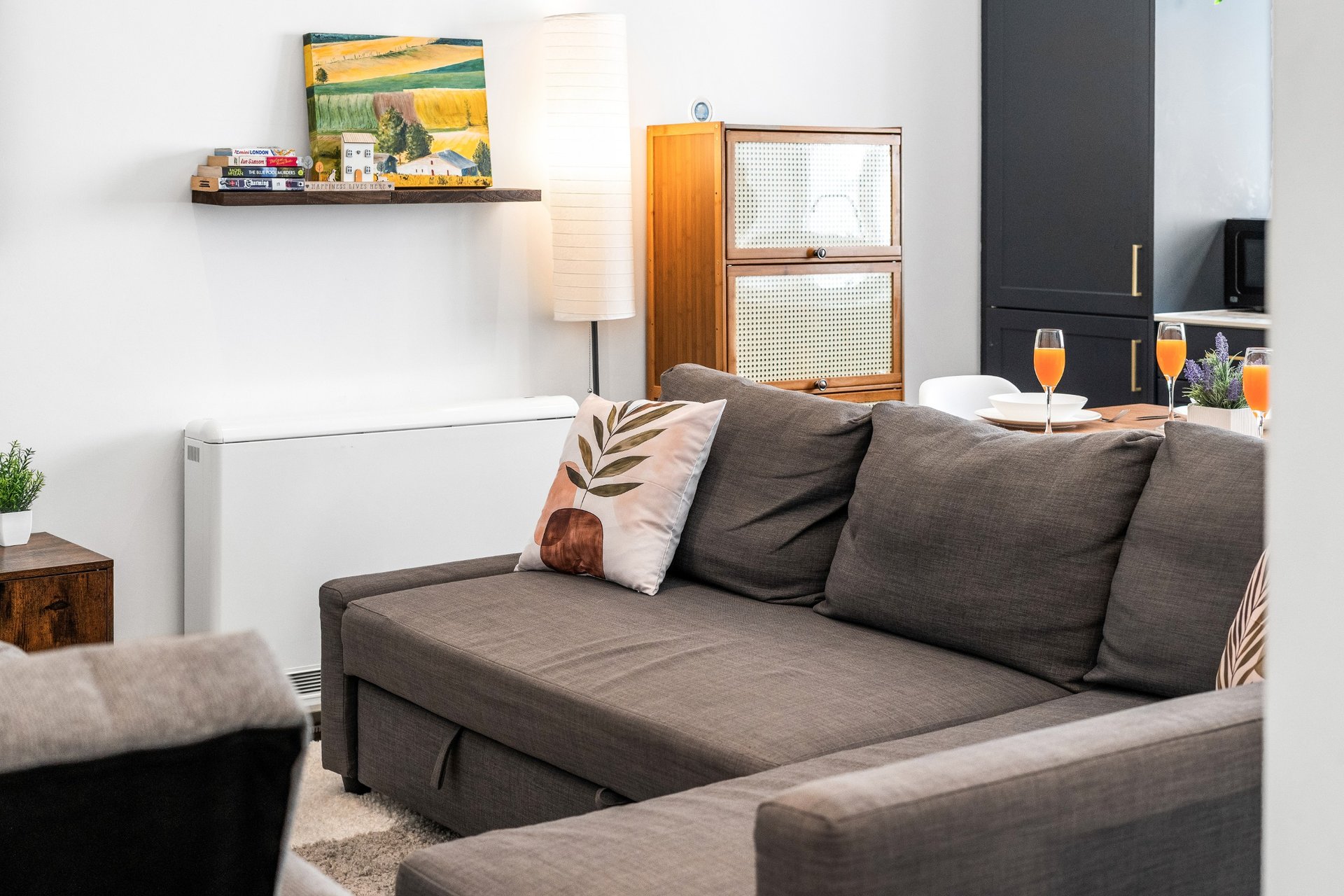 Modern living room with grey sofa, decorative cushions, wall shelving and warm lighting