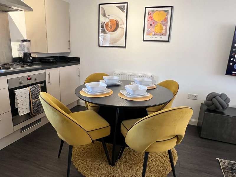 Open-plan kitchen and dining area with round table, yellow chairs, and place settings