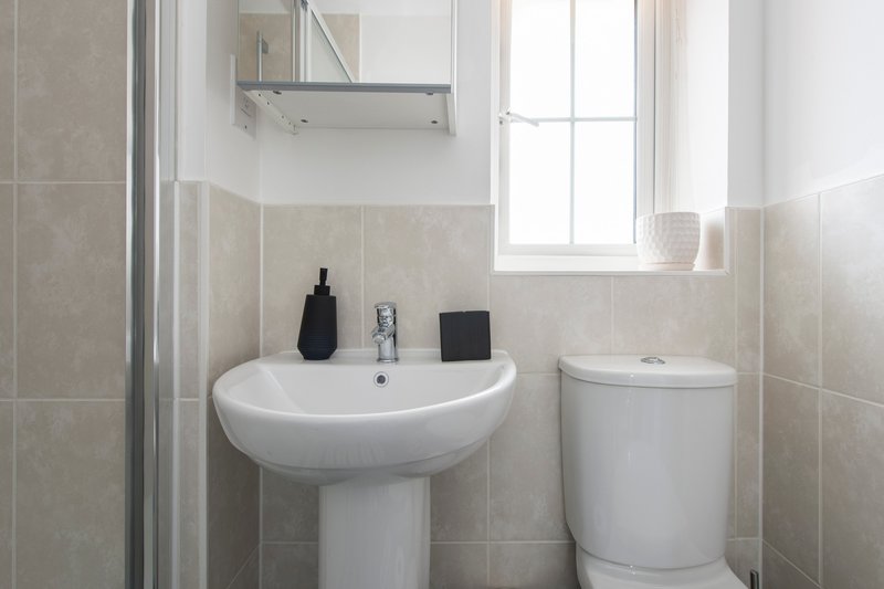 Small bathroom with pedestal sink, toilet, shower enclosure and window