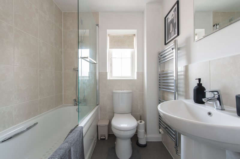 Modern bathroom with toilet, circular sink, shower enclosure and heated towel rail