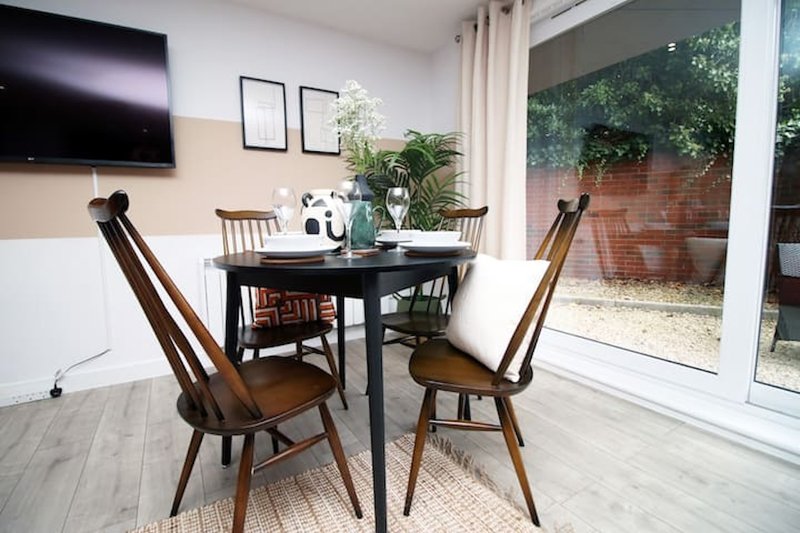 Modern dining area with black table, wooden chairs, wall-mounted TV and potted plants