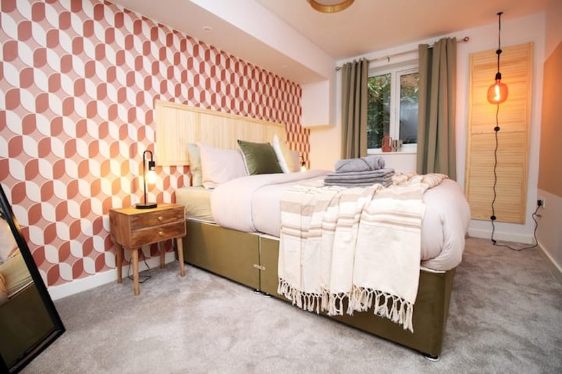 Modern bedroom with double bed, red checkered wallpaper, wooden nightstand and pendant lighting