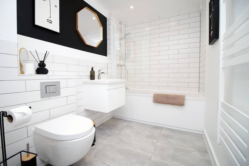 Modern bathroom with white subway tiles, wall-mounted toilet, sink, and shower enclosure with towel rail.