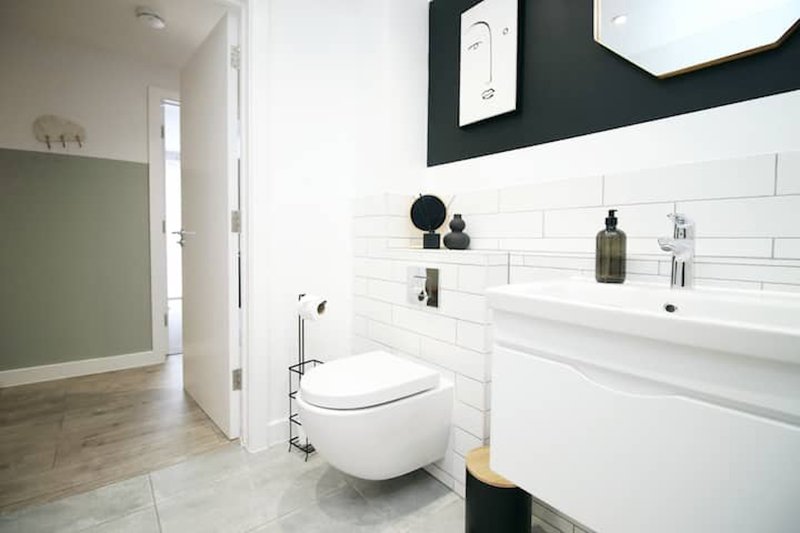 Modern bathroom with white subway tiles, wall-mounted toilet, sink, and black and white color blocking