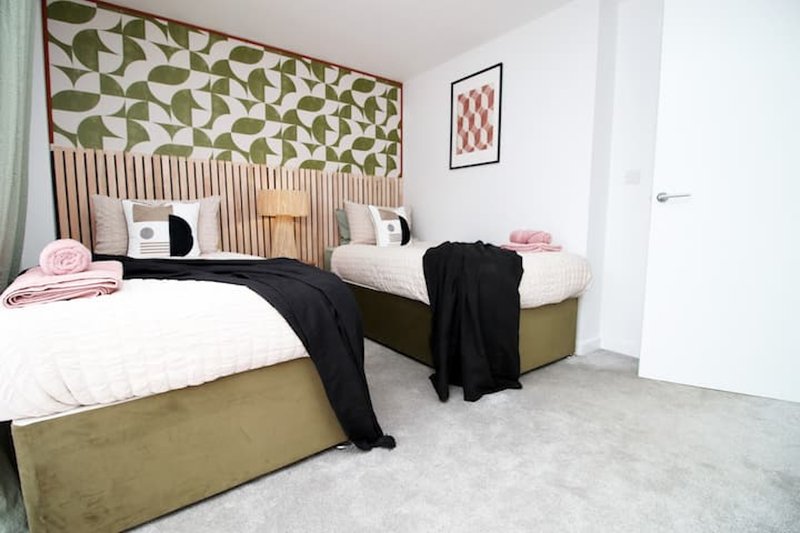 Modern bedroom with two single beds, geometric headboard, and minimal decor