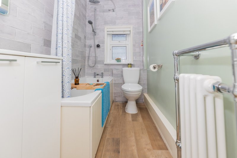 Modern bathroom with white vanity, toilet, heated towel rail and shower enclosure