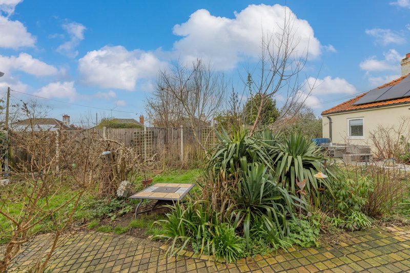 Garden patio area with paving stones, plants, and house visible in background