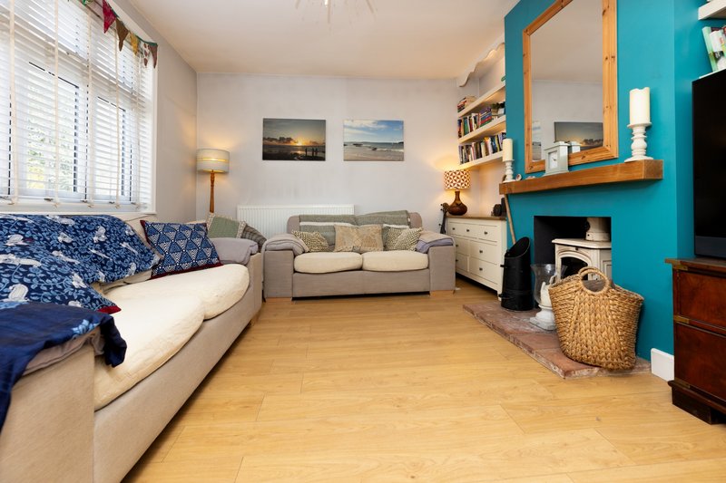Living room with sofa, daybed, wooden floor, turquoise accent wall and fireplace