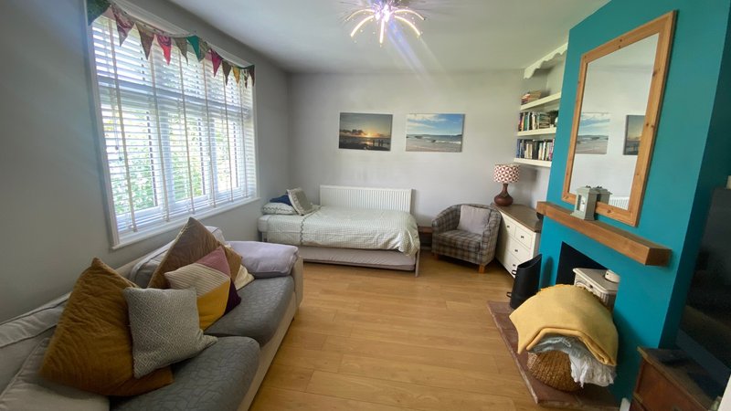 Living room with gray sofa, white daybed, wooden floor, turquoise accent wall and decorative cushions