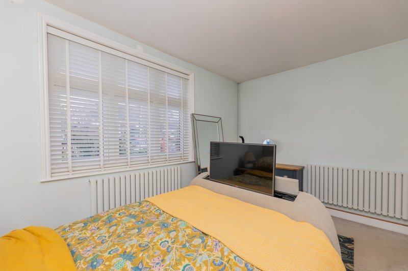 Bedroom with double bed, yellow bedding, TV on stand, window with shutters