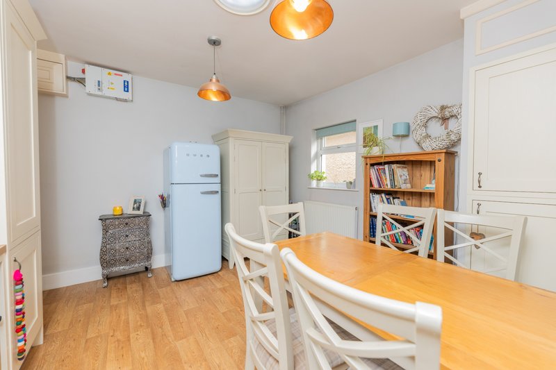 Kitchen-diner with wooden table, chairs, retro blue fridge, shelving and pendant lights