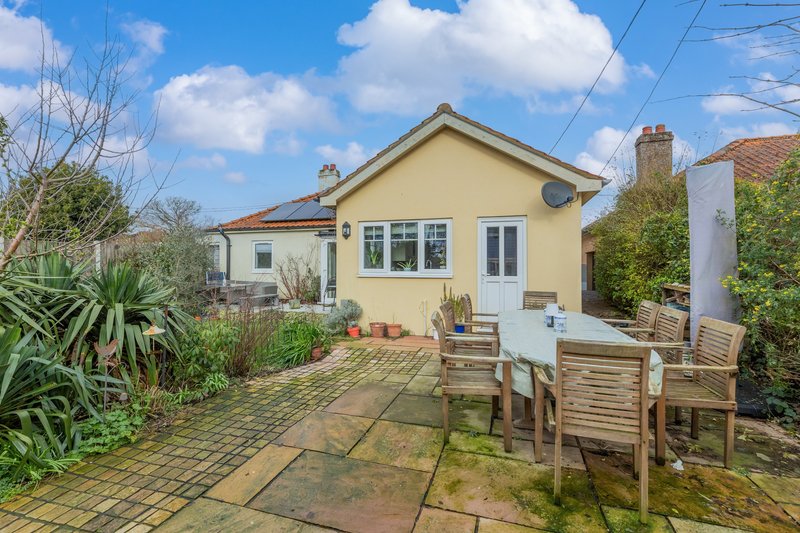 Yellow bungalow with patio, wooden deck, garden and brick driveway