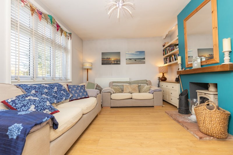 Bright living room with cream sofa, blue patterned cushions, wooden floor and turquoise shelving