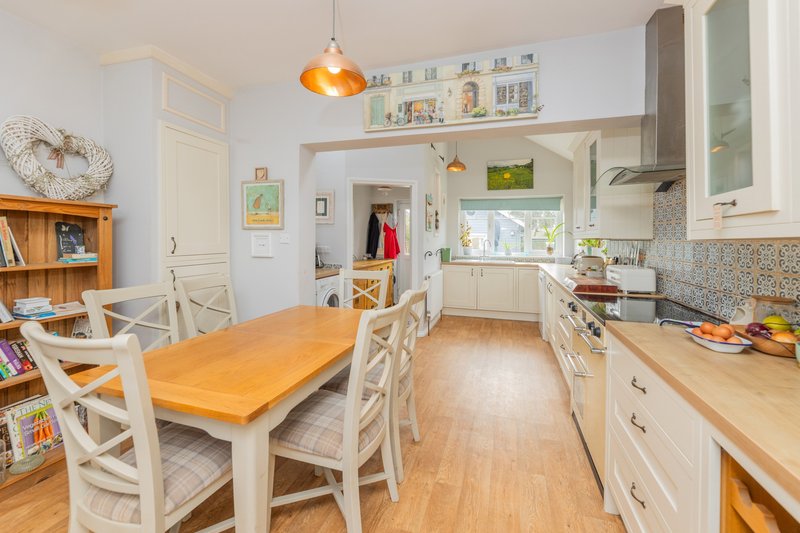 Bright kitchen-diner with cream cabinets, wooden table, dining chairs and pendant lighting