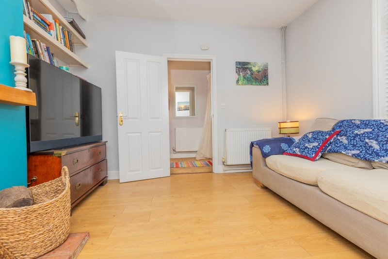 Bedroom with double bed, TV, wooden shelving, and wooden flooring throughout