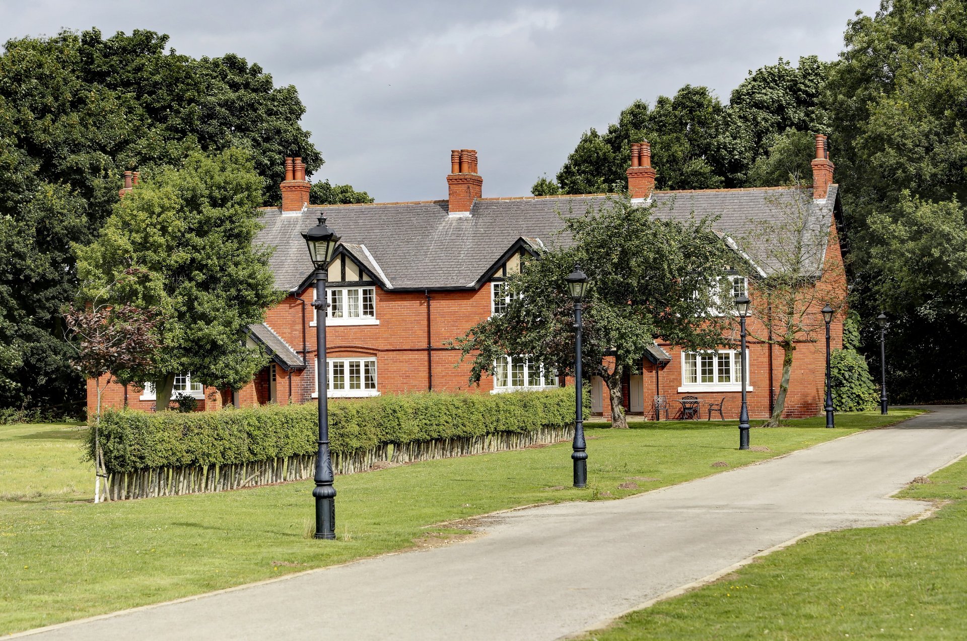 Traditional red-brick country house with half-timbered gables, manicured lawn and driveway