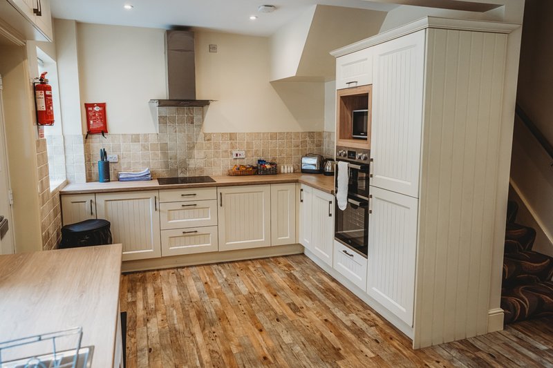 Modern kitchen with white cabinetry, wood flooring, tiled backsplash and built-in appliances