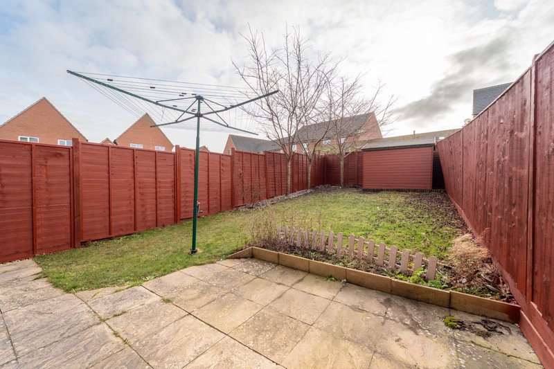 Enclosed garden area with red fencing, patio, raised beds and bare tree