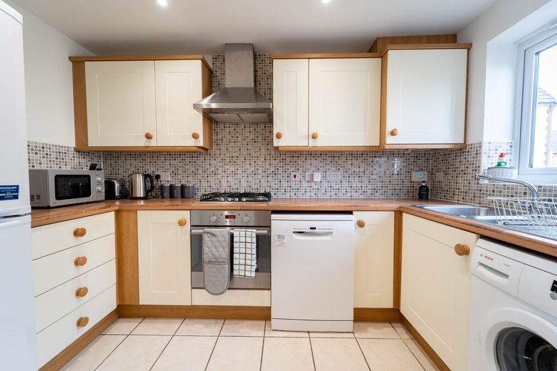 Modern kitchen with cream and wood cabinets, tiled backsplash, gas hob and integrated appliances