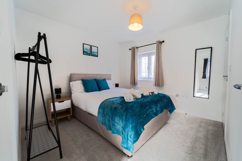 Modern bedroom with double bed, teal bedding, wooden nightstand, wall art and pendant light