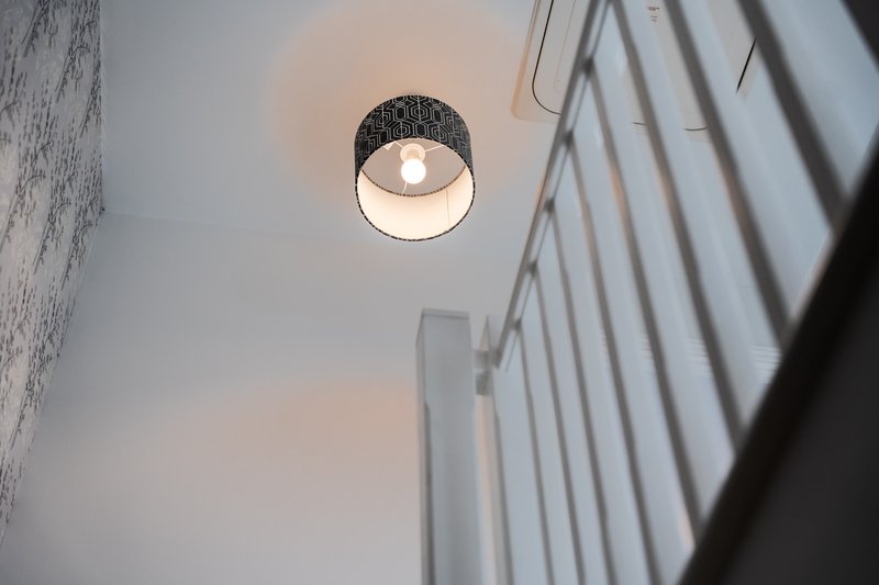 Ceiling-mounted pendant light fixture with textured shade in minimalist stairwell