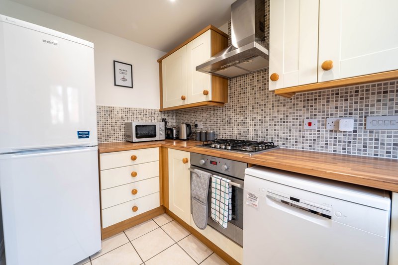 Modern kitchen with white and wooden cabinets, stainless steel appliances, tiled backsplash and worktops