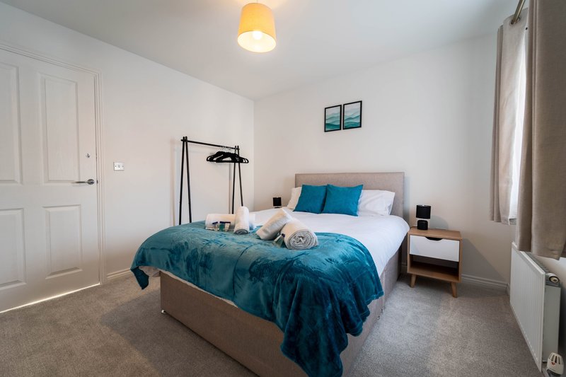 Modern bedroom with double bed, blue bedding, wooden nightstand and black floor lamp